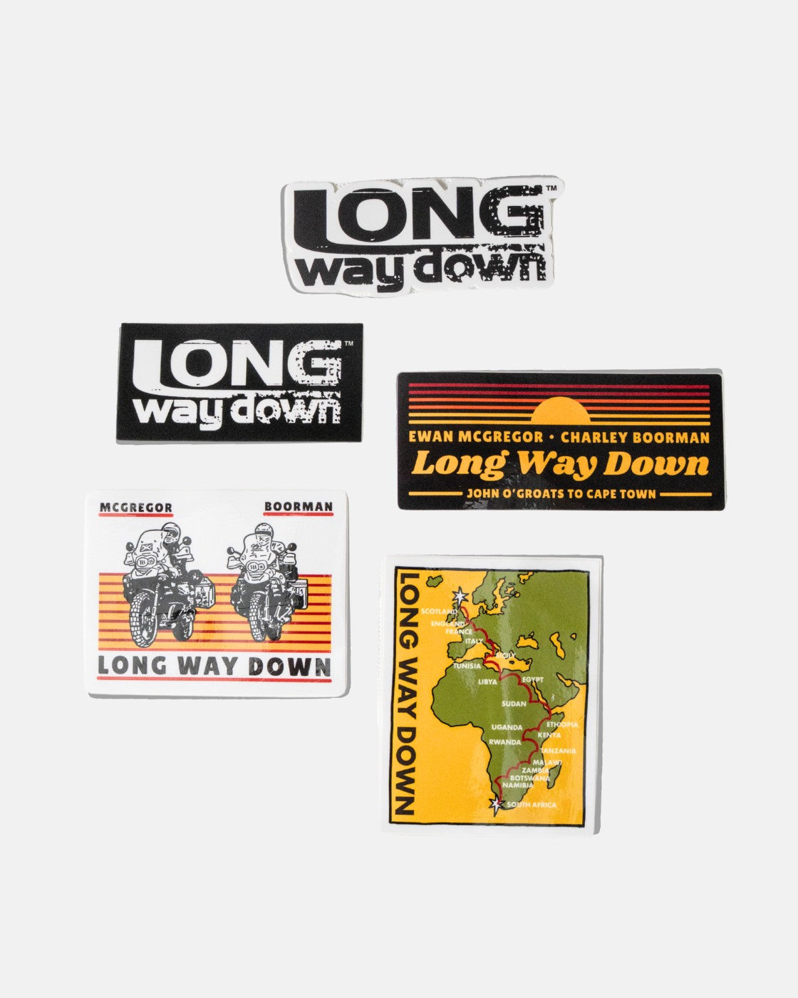 The Long Way Shop’s Long Way Down Sticker Pack includes five stickers: three with stylized text, one with two motorcyclists, and one featuring a yellow Scotland-to-South Africa route map—all referencing the motorcycle journey series.