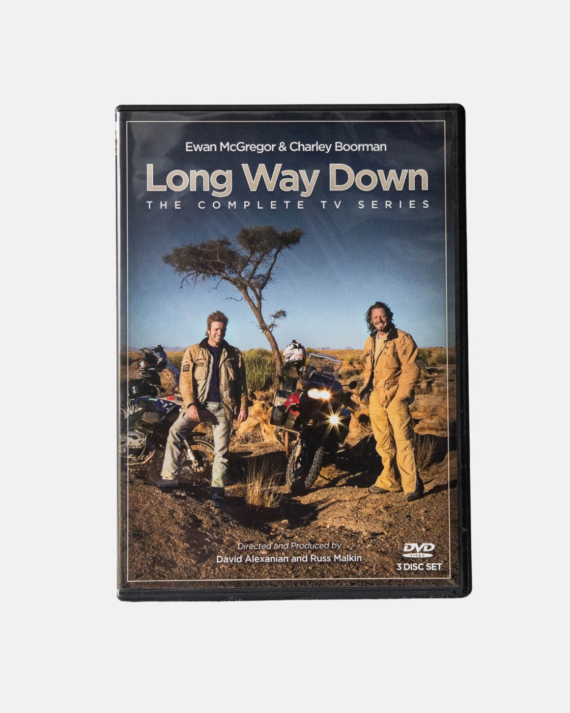 Long Way Shops Long Way Down DVD cover shows two men in motorcycle gear beside their bikes in a desert with a lone tree and blue sky.