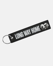 The Long Way Shop Keyring is a black fabric keychain with a silver ring, white LONG WAY HOME text, and two illustrated motorcycle helmets on the right.