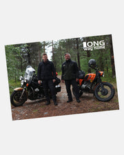 Two men in dark jackets stand by motorcycles on a forest path with trees behind them. LONG way home appears in the upper right. Available as an A2 Poster from Long Way Shop.